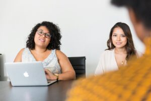deux femmes regardant une personne de l'autre côté de la table