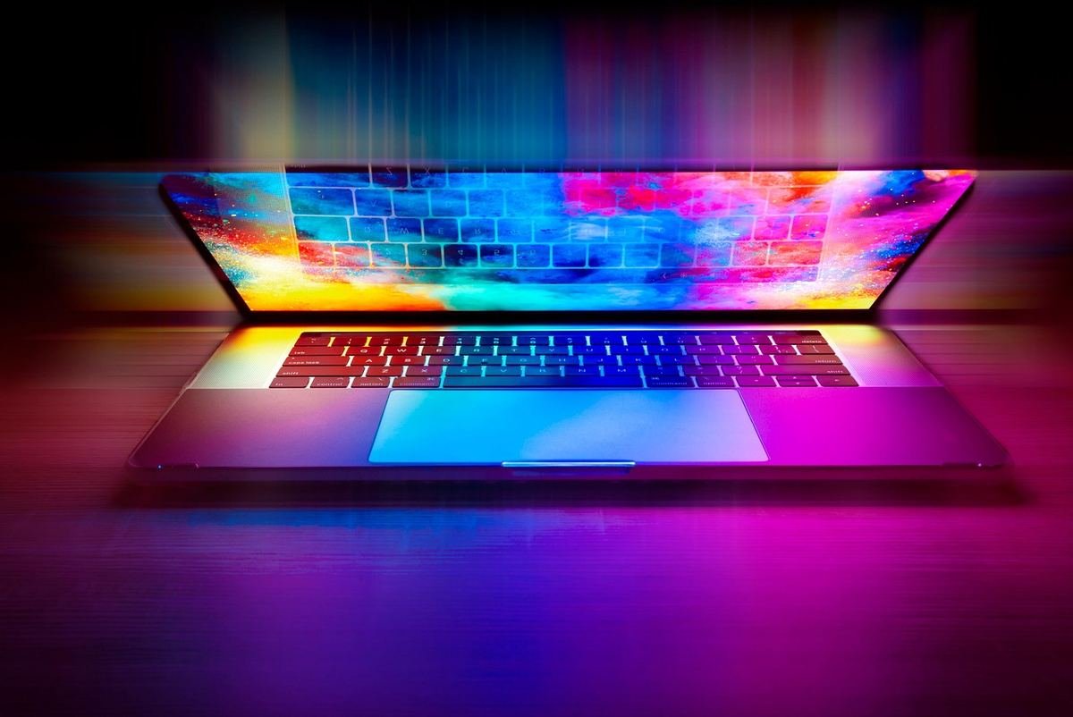 Ordinateur portable ouvert sur surface sombre, écran illuminé de couleurs vives multicolores