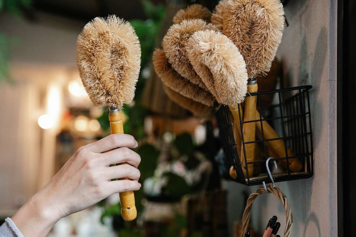 Une main saisit une brosse à poils naturels près d'un panier mural